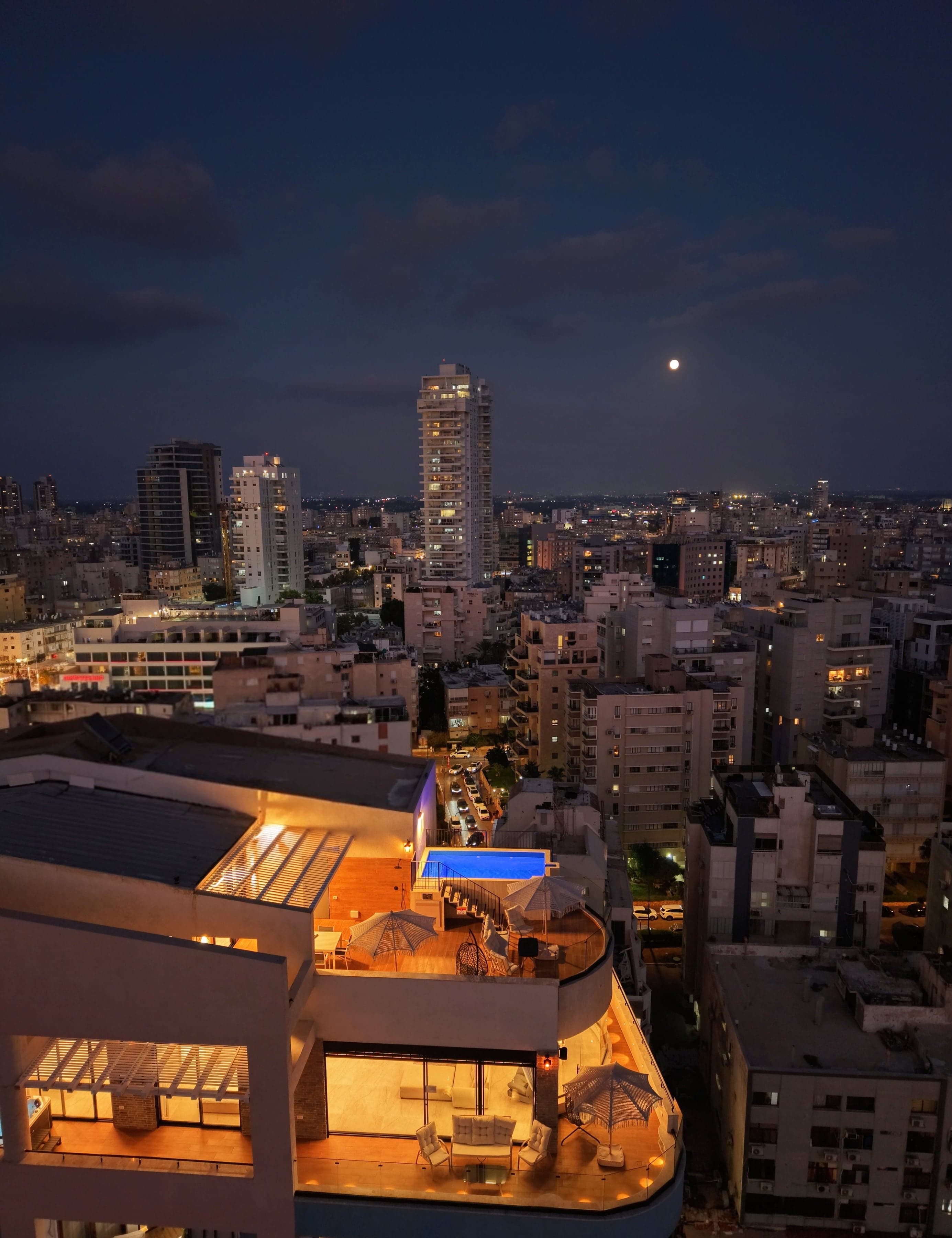 מתחם SEA VIEW בשעת דמדומים: שני הפנטהאוזים המוארים, הבריכה על הגג והעיר נתניה