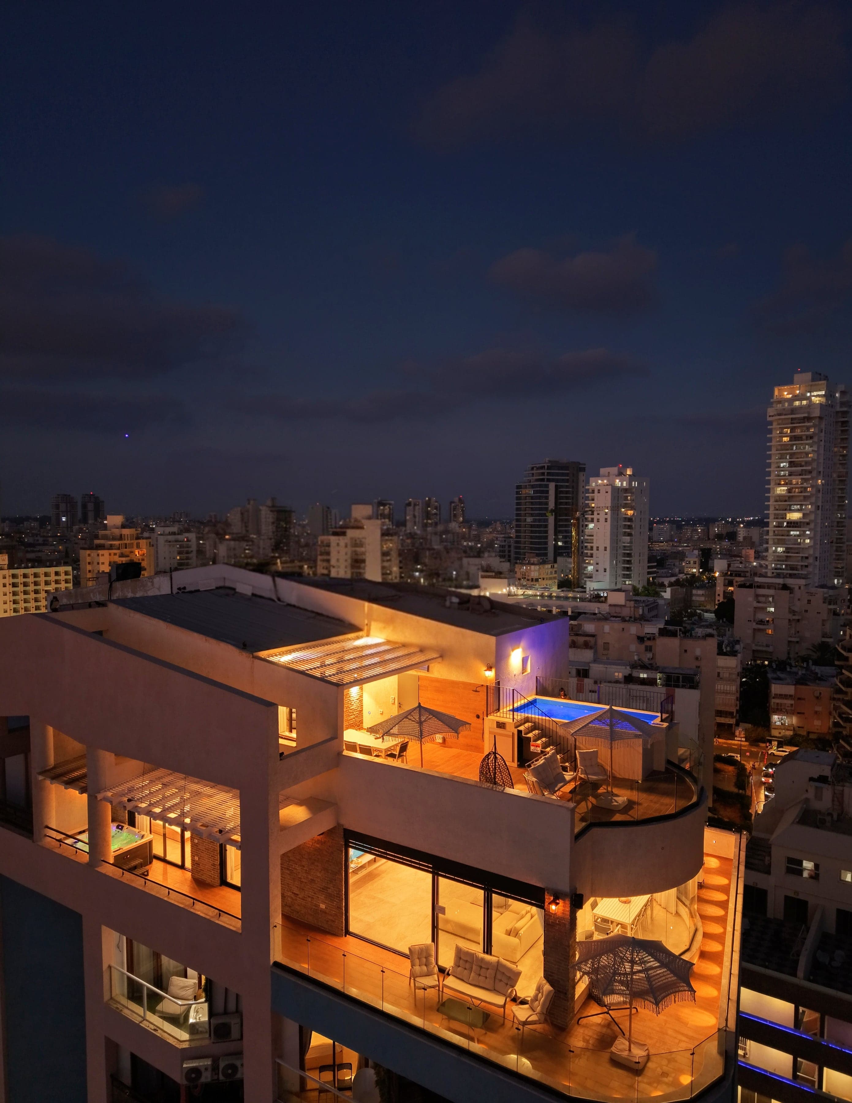 מתחם SEA VIEW בשעת דמדומים: שני הפנטהאוזים המוארים, הבריכה על הגג והעיר נתניה