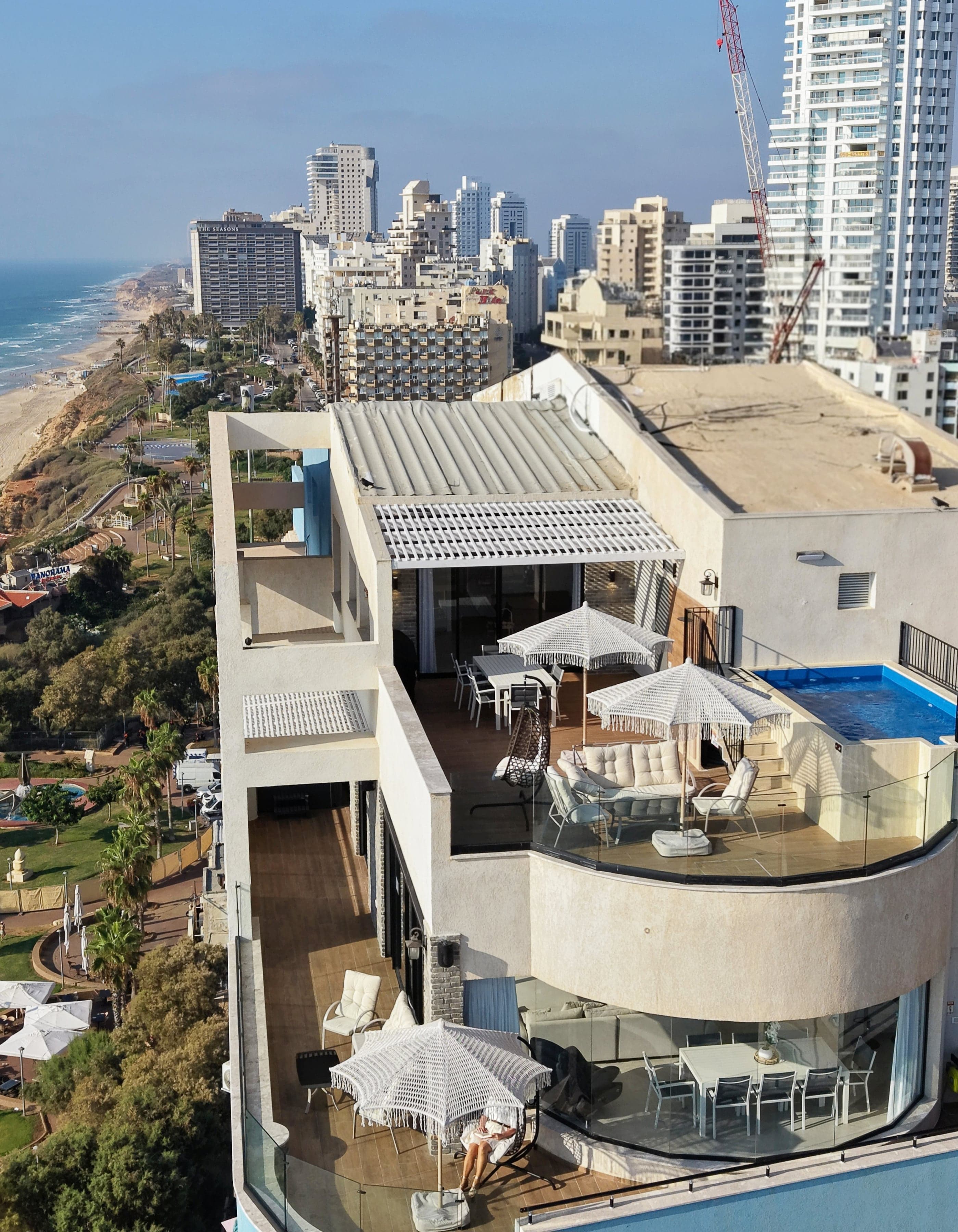 שני מפלסי SEA VIEW ביום: המרפסת ההיקפית וחדר האוכל המזוגג, ומעליהם מרפסת הגג והבריכה